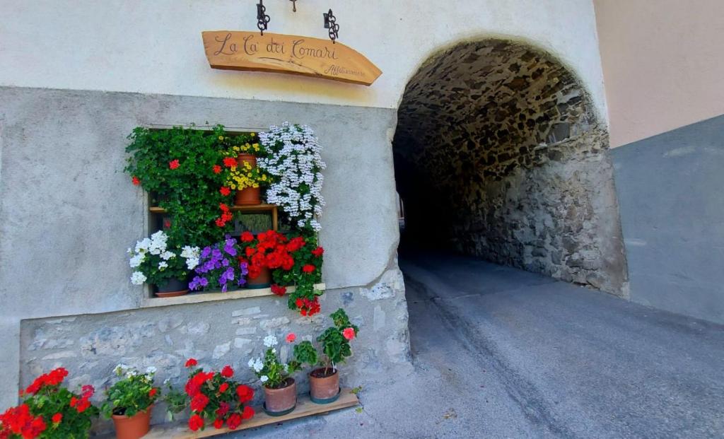 Capovalle的住宿－LA CA' DEI COMARI - Locanda da Tullio，建筑物一侧的窗户,有鲜花