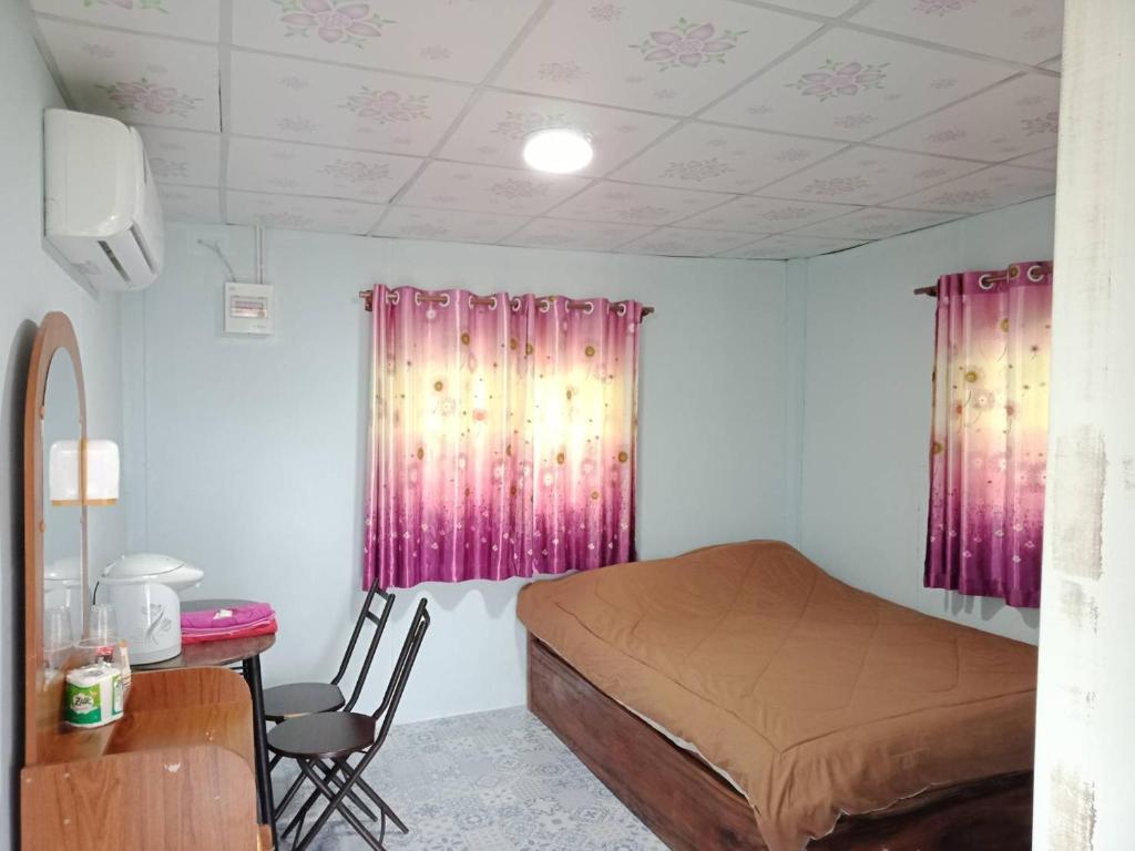 sypialnia z różowymi zasłonami, łóżkiem i biurkiem w obiekcie แม่ป้อมโฮมสเตย์ ลานกางเต้นท์ริมโขง w mieście Ban Muang