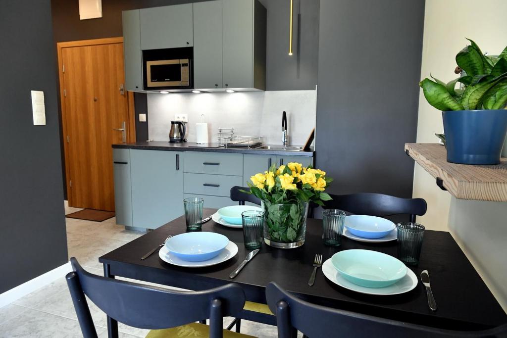 a black dining room table with blue plates and yellow flowers at Ach To Tu! Apartament Zator in Zator