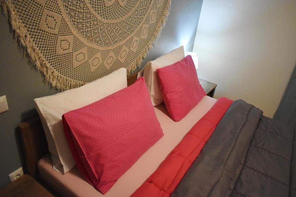 Una cama con almohadas rojas y blancas. en Rose's House, en Tríkala