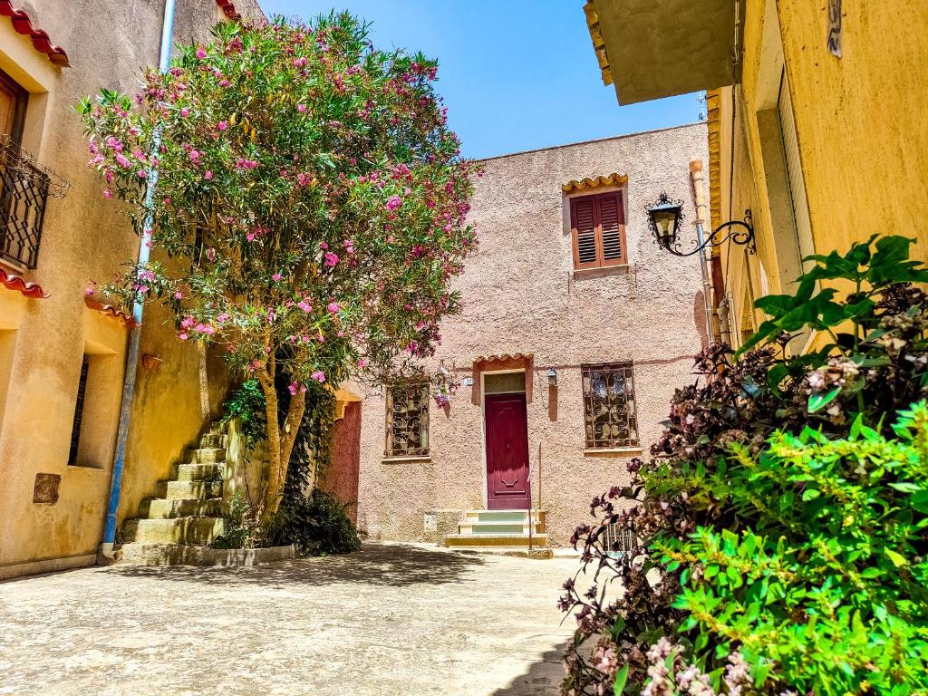 un edificio con una puerta roja y un árbol con flores rosas en SweetHome in Erice Vetta, en Erice