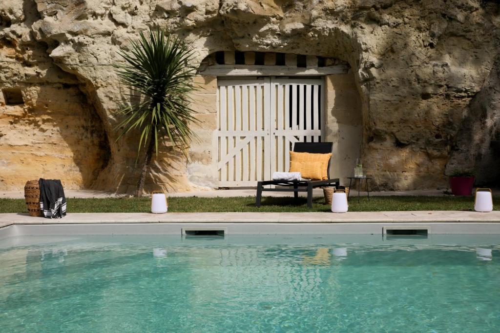 a house with a swimming pool in front of a stone wall at Domaine du Val Sauvage in Langeais
