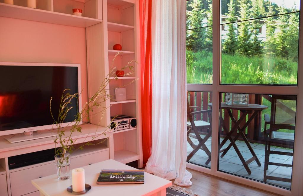ein Wohnzimmer mit einem TV und einem Balkon in der Unterkunft Štýlový apartmán v srdci Donovalov in Donovaly