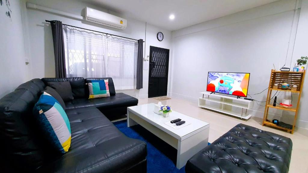a living room with a black leather couch and a tv at HDY 16 Home in Hat Yai