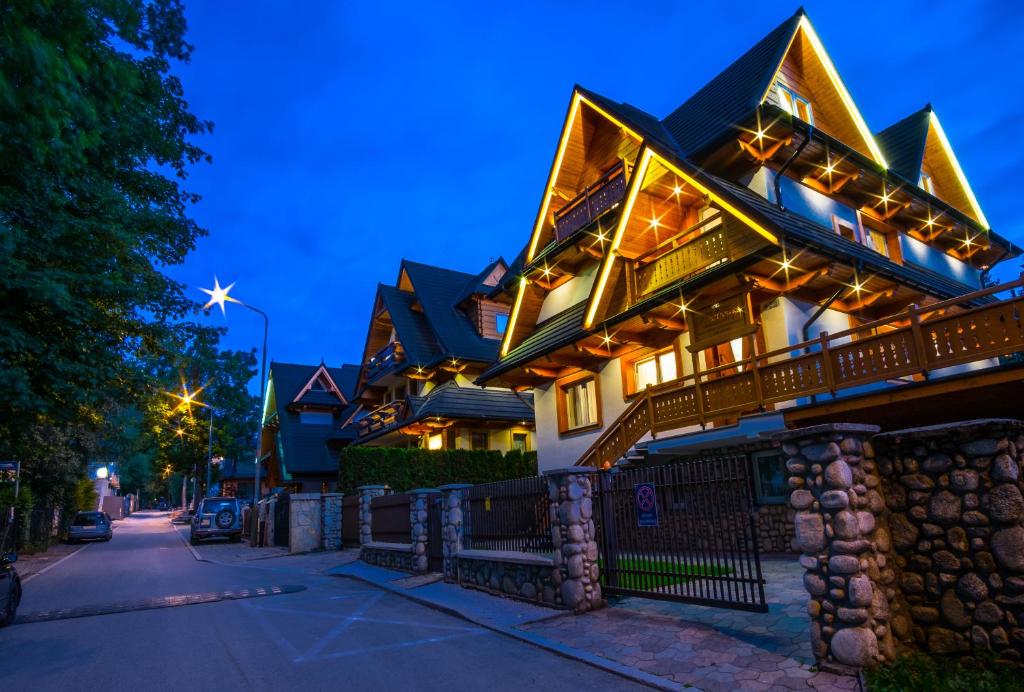 a large house with lights on the facade at night at Willa Modrzejówka in Zakopane