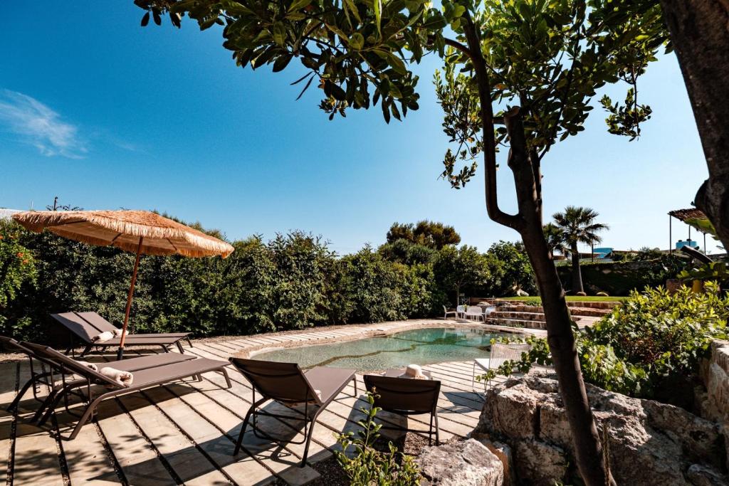 a patio with chairs and an umbrella and a pool at Villa Gemma - Sea Access & Private Pool in Polignano a Mare