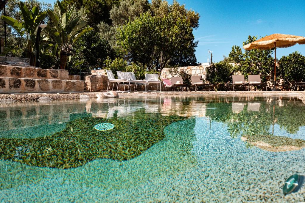 a pool of water with chairs and an umbrella at HelloApulia Villa Gemma with private eco pool and with direct access to the sea in Polignano a Mare