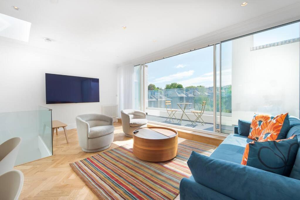 uma sala de estar com um sofá azul e uma grande janela em Stunning Two Bed Apartment RH8 em Londres