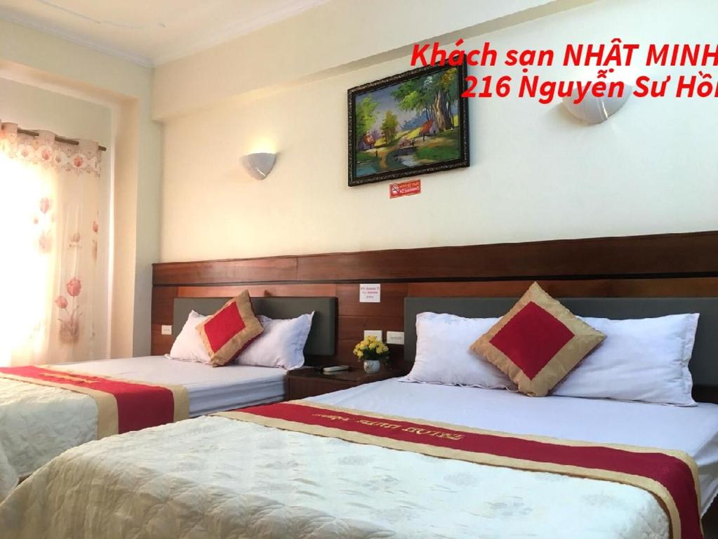 a hotel room with two beds and a sign on the wall at Khách sạn NHẬT MINH Cửa Lò in Cửa Lò