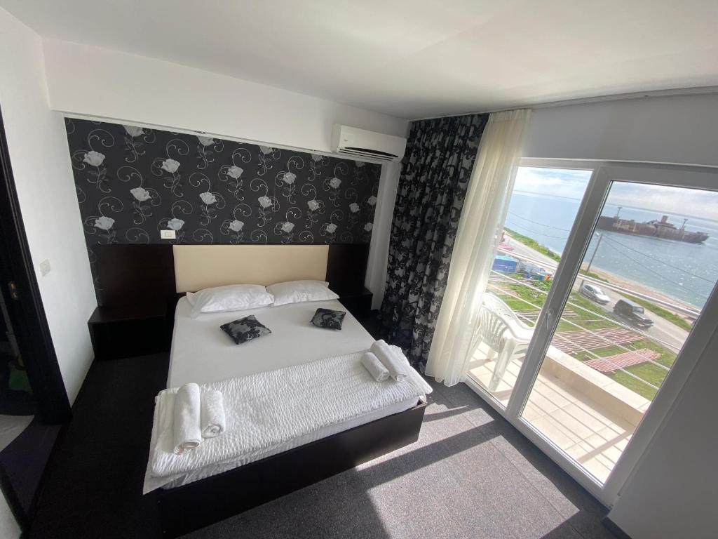 1 dormitorio con cama y vistas al océano en Pensiunea Maria Costinesti, en Costinesti