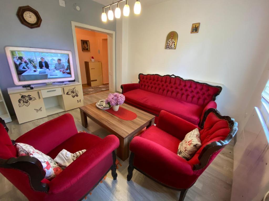 a living room with two red chairs and a tv at Vila Ilidža in Banja Koviljača