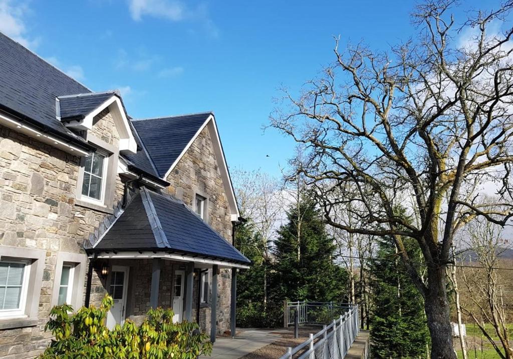 a stone house with a tree in front of it at Capercaillie in Killin