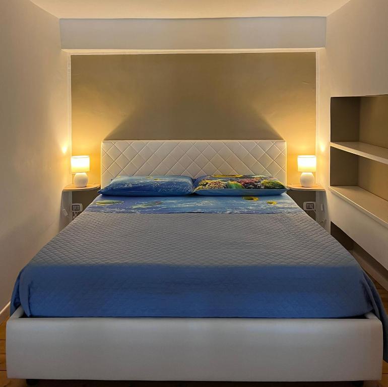 a bedroom with a bed with blue sheets and two lamps at ʜᴏᴍᴇ sᴡᴇᴇᴛ ʜᴏᴍᴇ in Bagnara Calabra