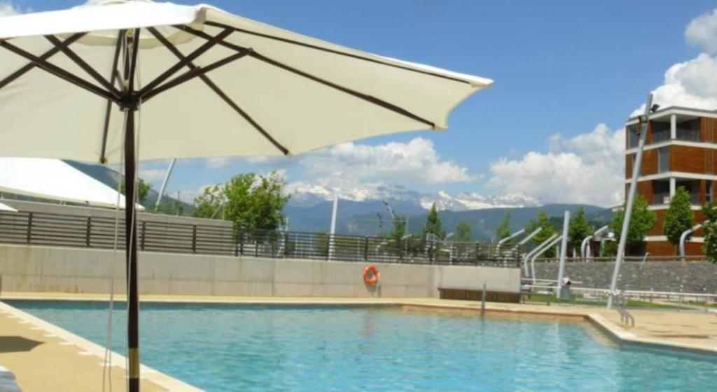 a pool with an umbrella next to a building at Margas Golf Apartment in Sabiñánigo