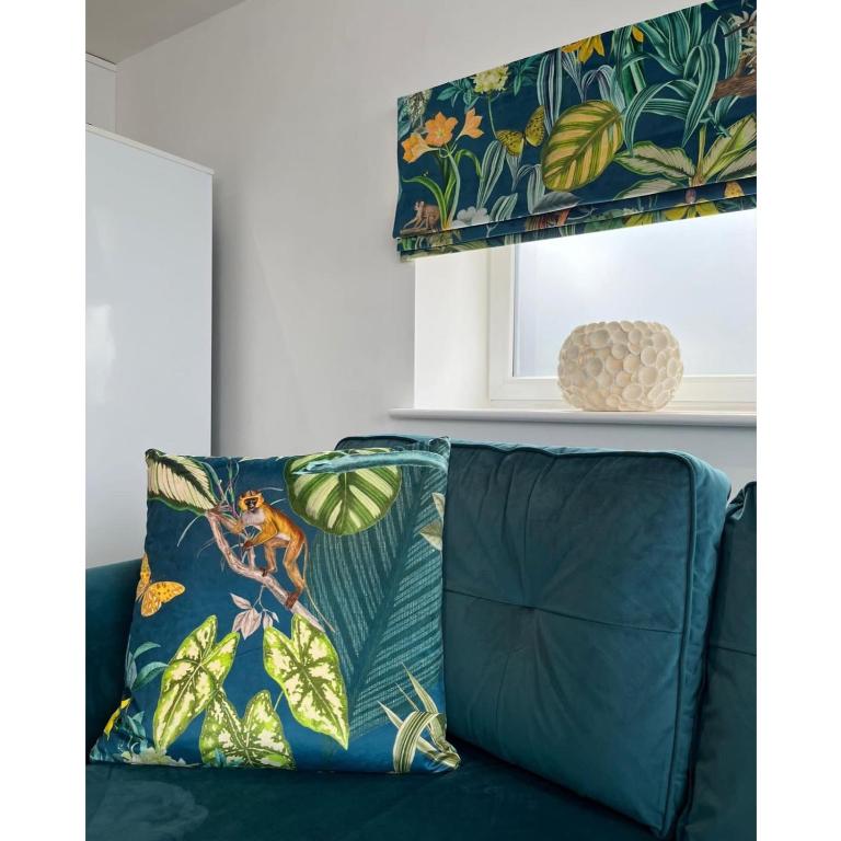 - un canapé vert avec un oreiller bleu et une fenêtre dans l'établissement The Hideout (Garden Flat, 4 Dragon Road), à Harrogate