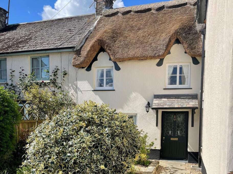 a white house with a thatched roof at Beautiful 1 bed thatched cottage in Dolton