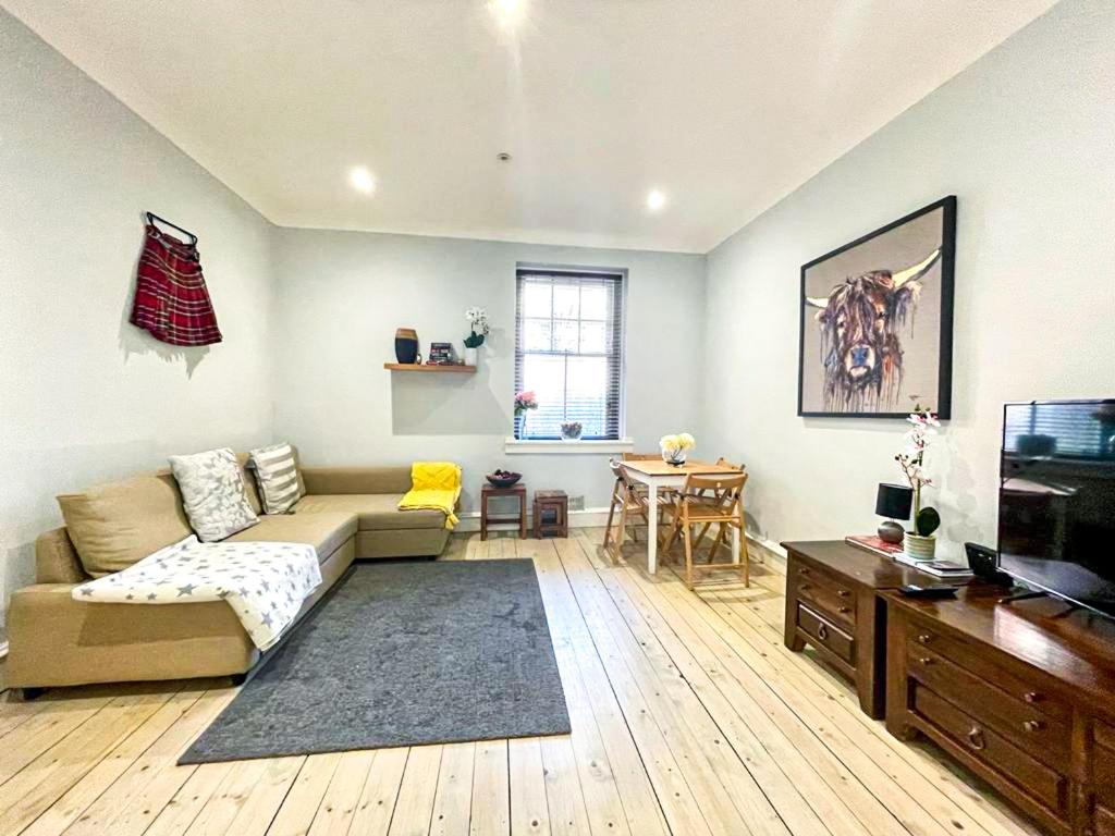 Una sala de estar con un sofá y un televisor. en Stunning 2 Bed Apt Nr The Royal Mile & The Castle, en Edimburgo