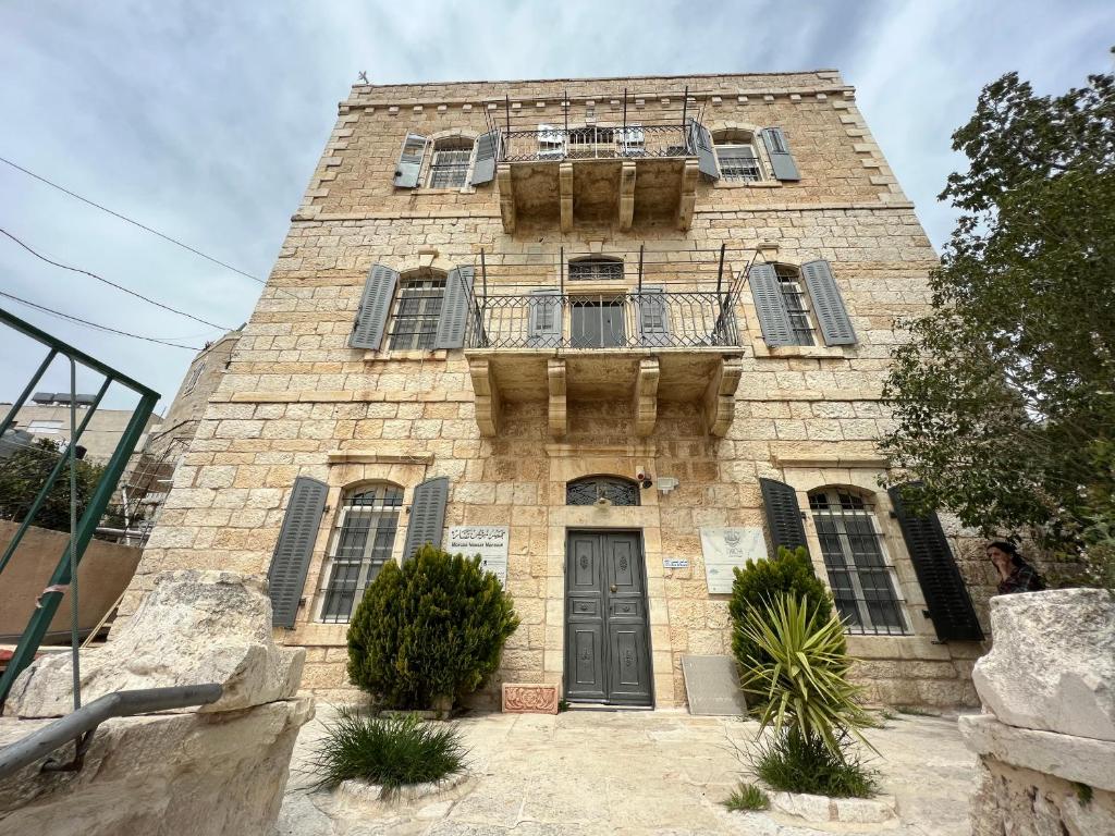 - un vieux bâtiment en pierre avec un balcon et une porte dans l'établissement Ma'an lil-Hayat Boutique Hotel, à Bethléem