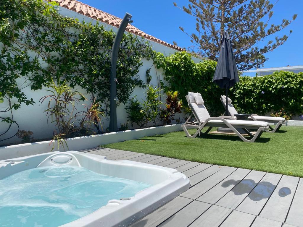 a hot tub in a yard with a chair and an umbrella at Villa Palmera in Maspalomas