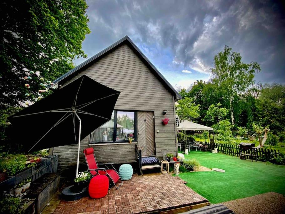a house with an umbrella and chairs on a lawn at Amazing little house on an island with garden in Riga