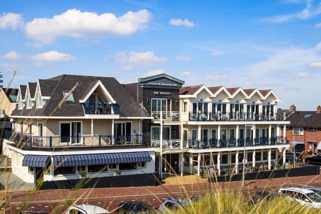 a large white building with balconies on a street at Strandhotel de Vassy in Egmond aan Zee