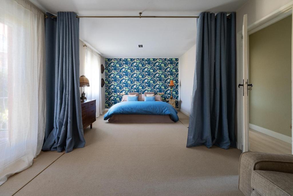 a bedroom with a blue bed and blue curtains at Casa Palomera - Casa completa con jardín, gimnasio y garaje privados in León