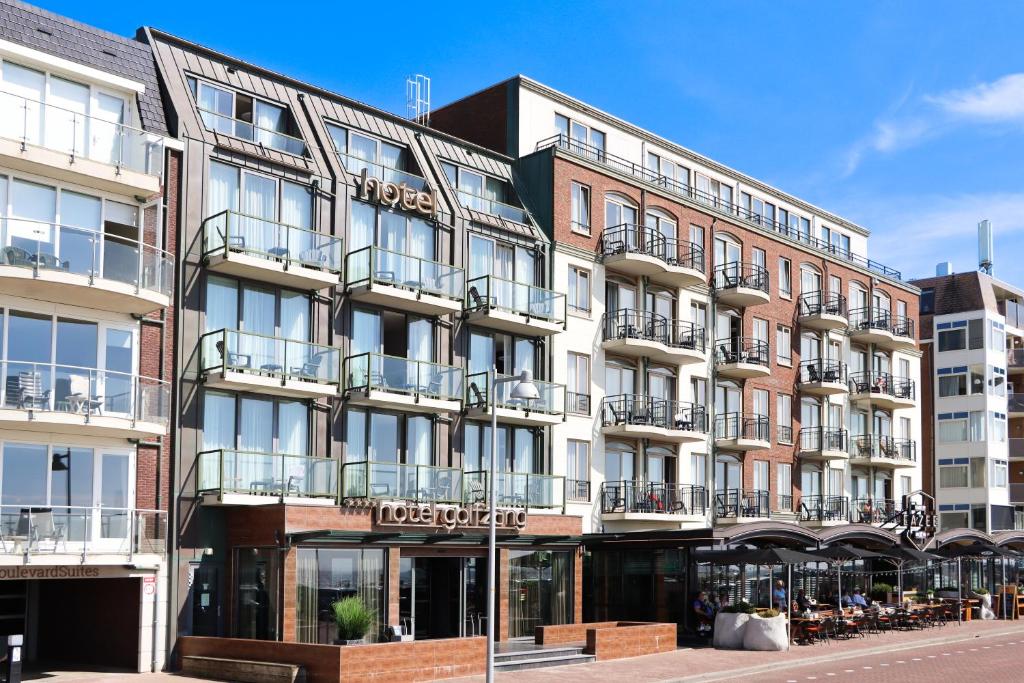 an apartment building with balconies on a street at Strandhotel Golfzang in Egmond aan Zee