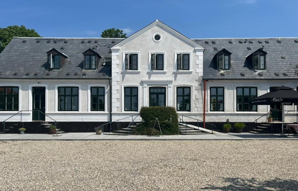 a large white building with black windows on a street at Lynæs Hotel in Hundested