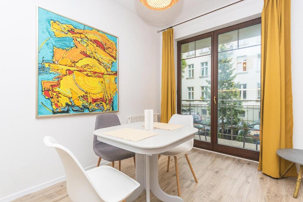 索波特的住宿－Pomorskie Apartamenty Baltic House，一间用餐室,配有白色的桌椅和绘画作品