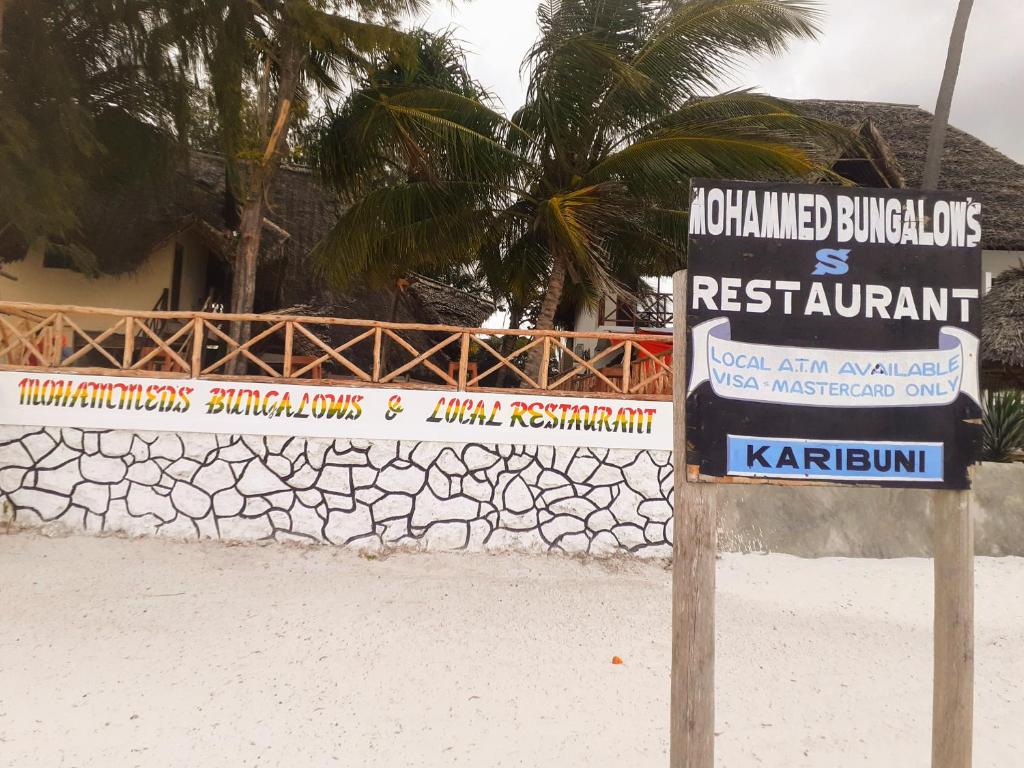 a sign on the beach in front of a building at Mohammed Bungalows and Restaurant in Matemwe