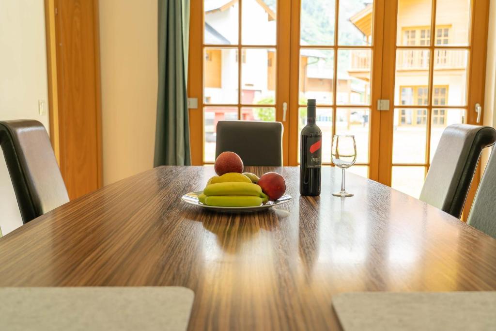 - une table avec une assiette de fruits et une bouteille de vin dans l'établissement Andrea 1 by SMR Rauris Apartments inc SPA and National Summercard - near Gondola, à Rauris