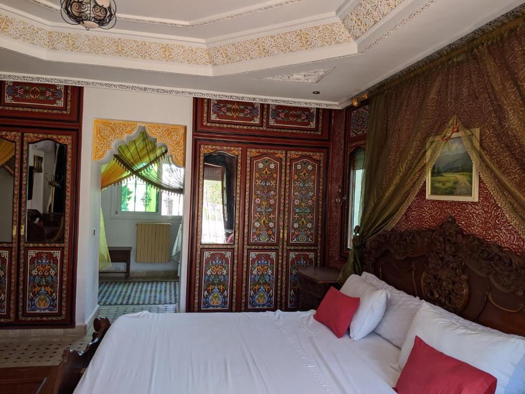 a bedroom with a white bed with red pillows at Malabata Guest House in Tangier