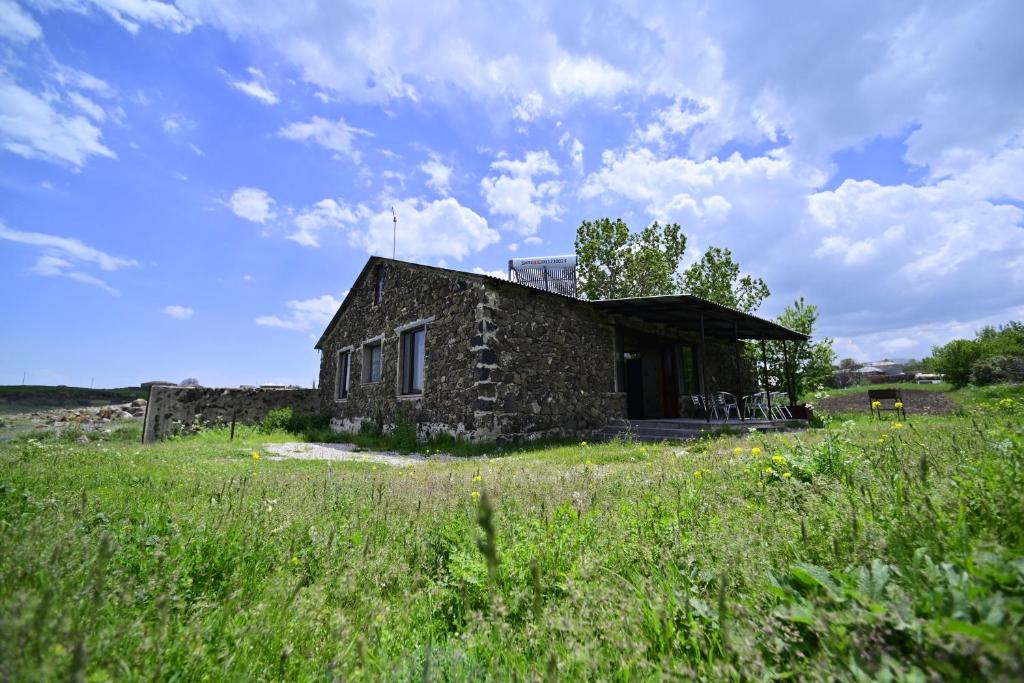 une ancienne maison en pierre dans un champ d'herbe dans l'établissement Sevan Tarsus Guesthouse, à Tsovazard