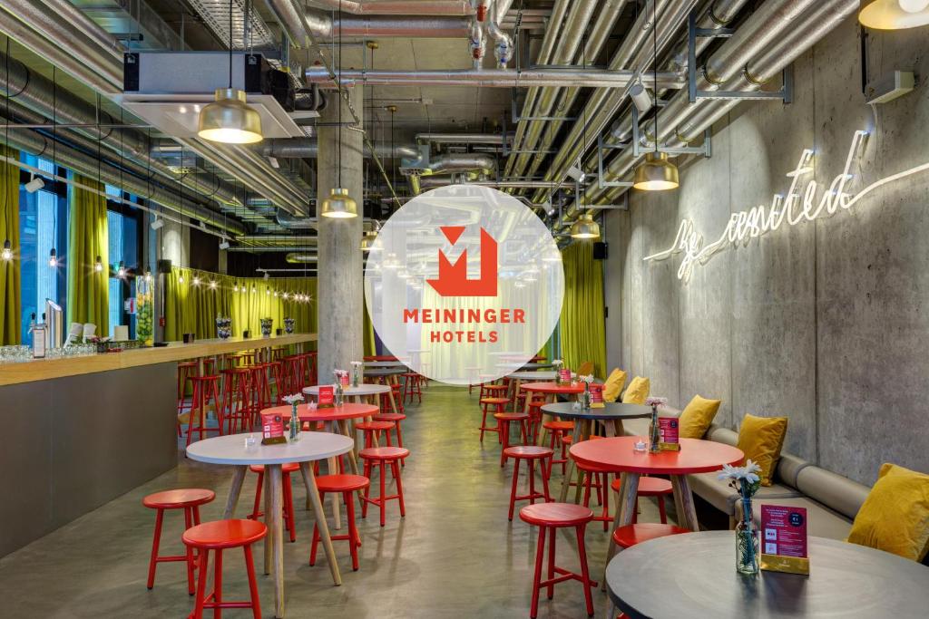 a restaurant with tables and red stools at MEININGER Hotel Berlin East Side Gallery in Berlin