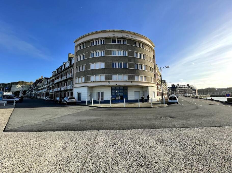 een groot gebouw met auto's geparkeerd voor het bij Le Panoramique. Appartement vue mer. in Saint-Valéry-en-Caux
