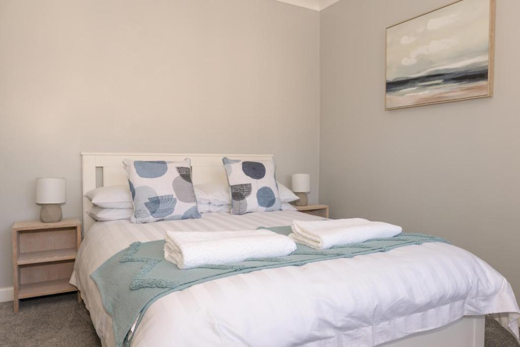 um quarto com uma cama com lençóis brancos e almofadas em 2 Park Court em Ilfracombe