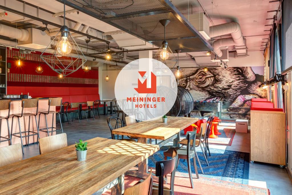 a restaurant with wooden tables and a sign that reads member industries at MEININGER Hotel Berlin Tiergarten in Berlin