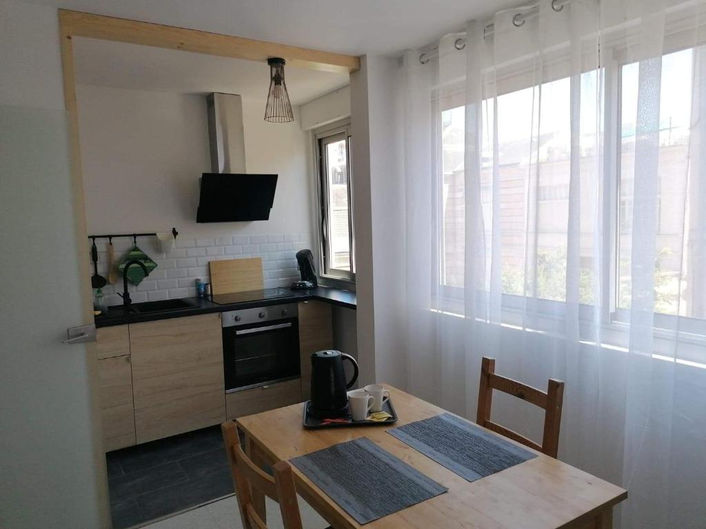 uma cozinha com uma mesa de madeira e uma cozinha com um fogão em Appartement centre ville avec parking privatif em Dijon