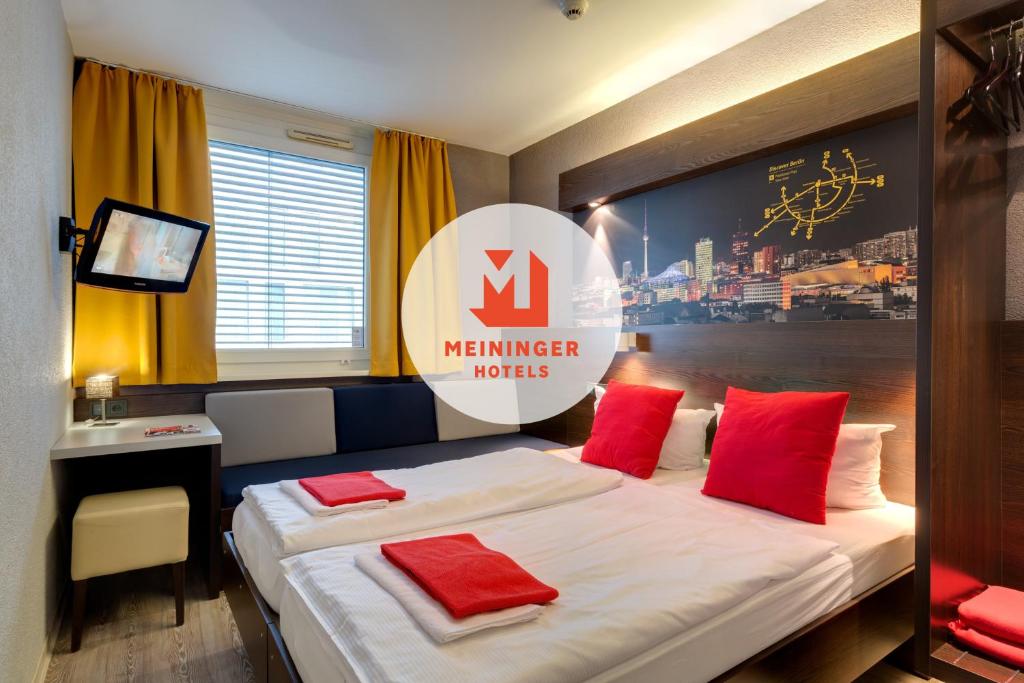 Cette chambre comprend un lit avec des oreillers rouges. dans l'établissement MEININGER Hotel Berlin Hauptbahnhof, à Berlin