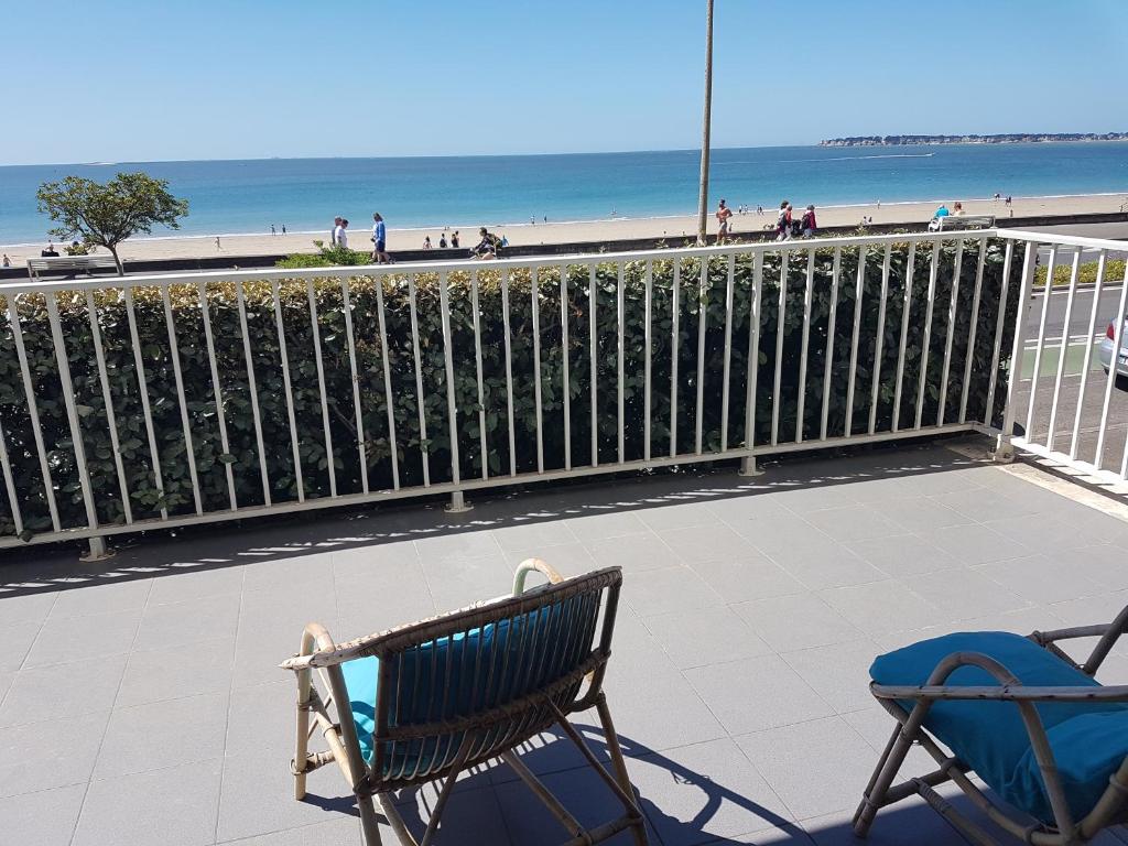 d'un banc et de 2 chaises sur un balcon donnant sur la plage. dans l'établissement Saint Clair, à La Baule