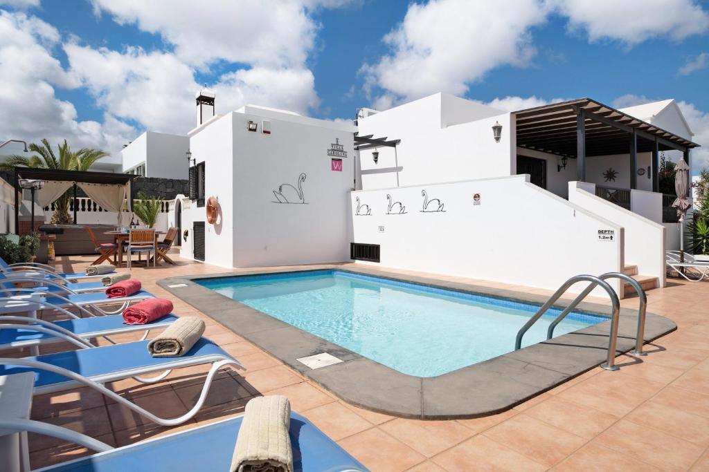 a pool with lounge chairs next to a house at Villa Carolina in Tías