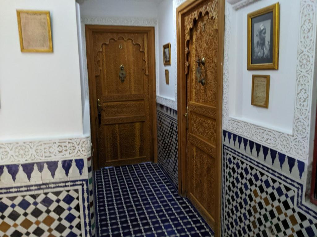 a hallway with a wooden door and tiled floors at Malabata Guest House in Tangier
