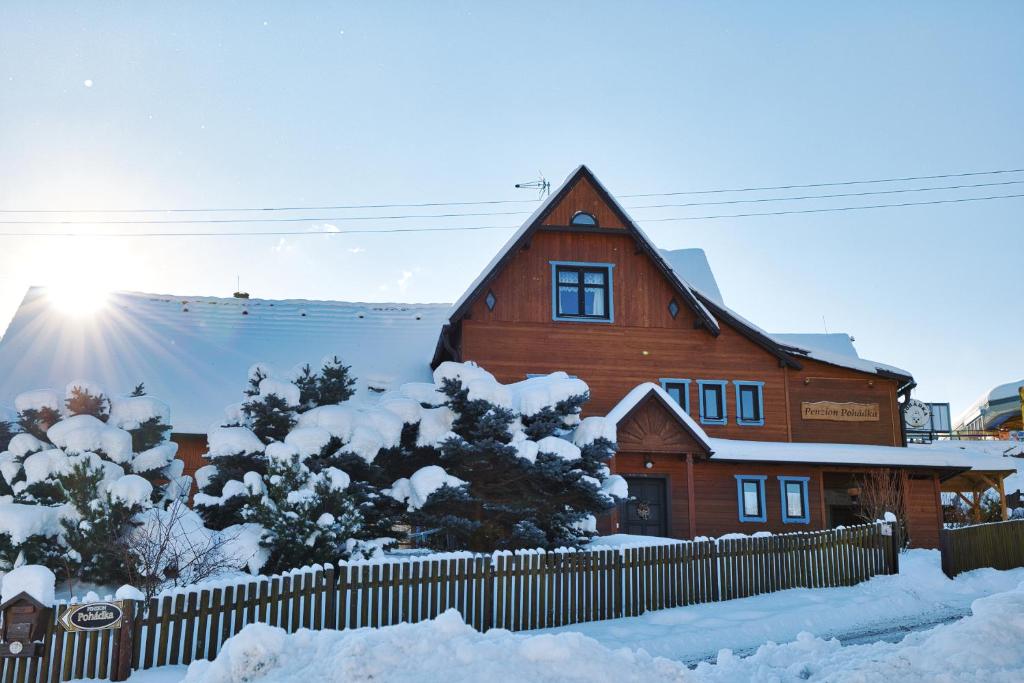 una casa de madera con nieve delante en Penzion Pohádka, en Malá Morávka