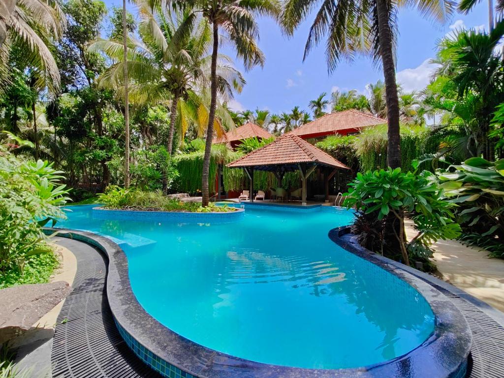 a swimming pool at a resort with palm trees at SaffronStays Kimaya, Alibaug in Alibaug