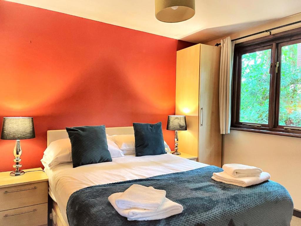 1 dormitorio con 1 cama con pared roja en Wren 21-Hot Tub-Woodland Lodges-Tenby-Camarthenshire, en Carmarthen