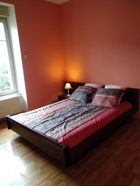 a bed in a bedroom with a red wall at Les Chambres de Marvejols in Marvejols