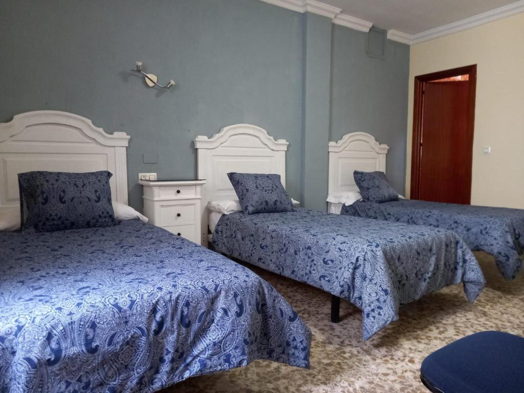 a bedroom with two beds with blue and white sheets at Hotel Medina Centro in Jerez de la Frontera