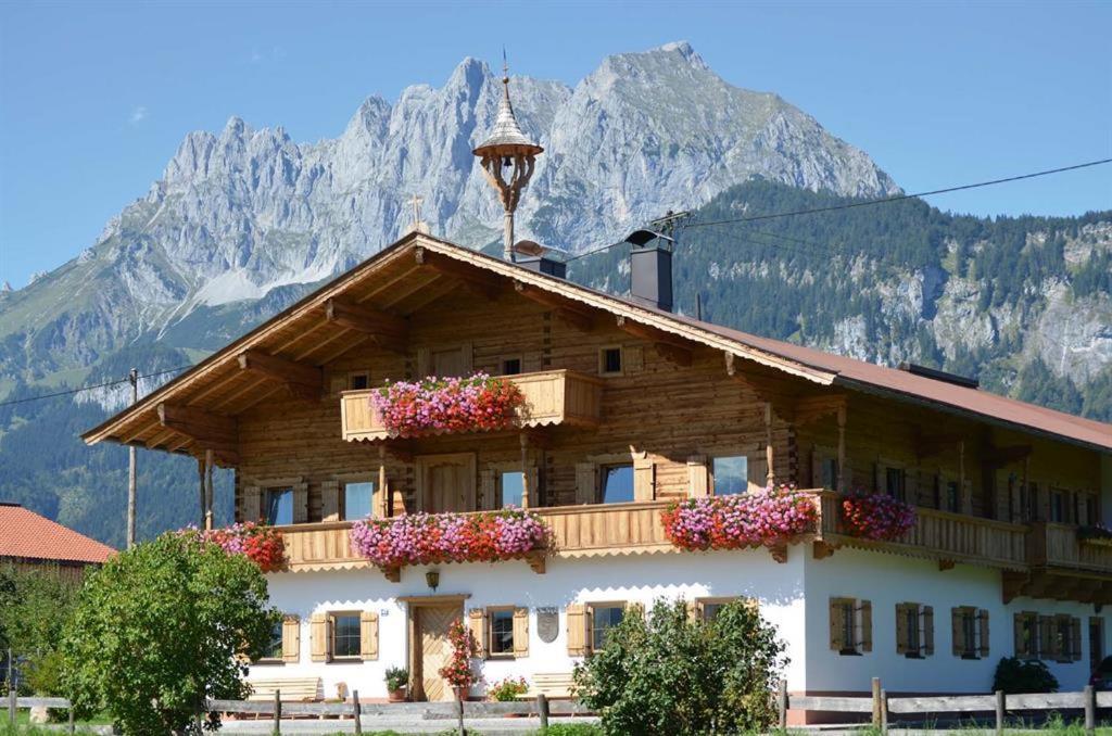ein Gebäude mit Blumen auf dem Dach mit Bergen im Hintergrund in der Unterkunft Kröpflhof in Sankt Johann in Tirol