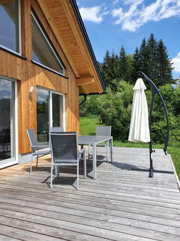 魏森湖的住宿－Ferienhäuser Seetraum，木甲板配有桌子和遮阳伞