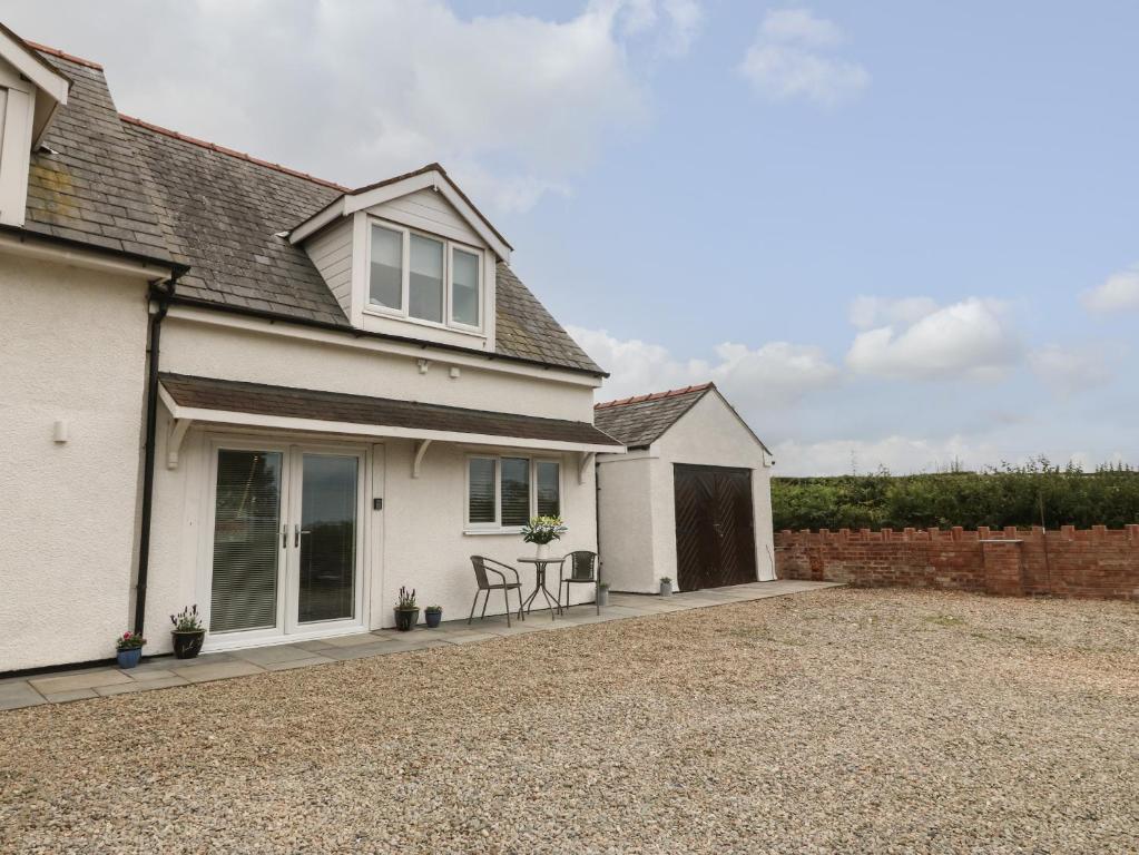 a house with a gravel driveway in front of it at Bryn Eglwys Bach in Llanfairpwllgwyngyll